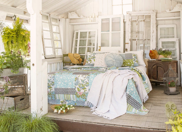 Cozy bedroom with floral bedding and decorative pillows in a bright, sunlit room.