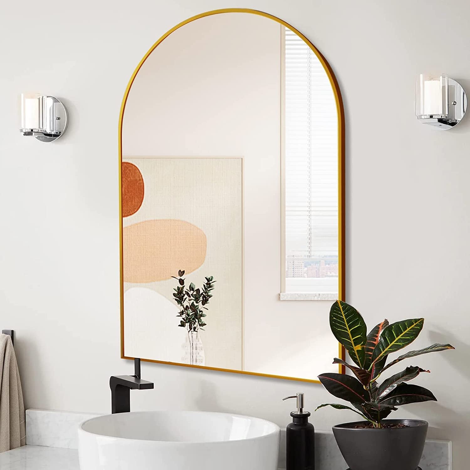 24x36 Inch Gold Metal Framed Arched Mirror mounted above a bathroom sink, complementing modern lighting and minimalist wall art.
