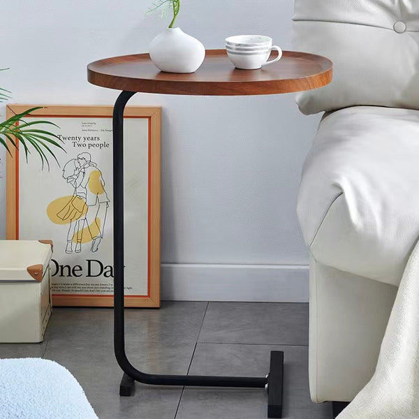 Brown C-shaped Side Table next to a white couch, styled with a vase and cup, perfect for living room or reading nook decor.