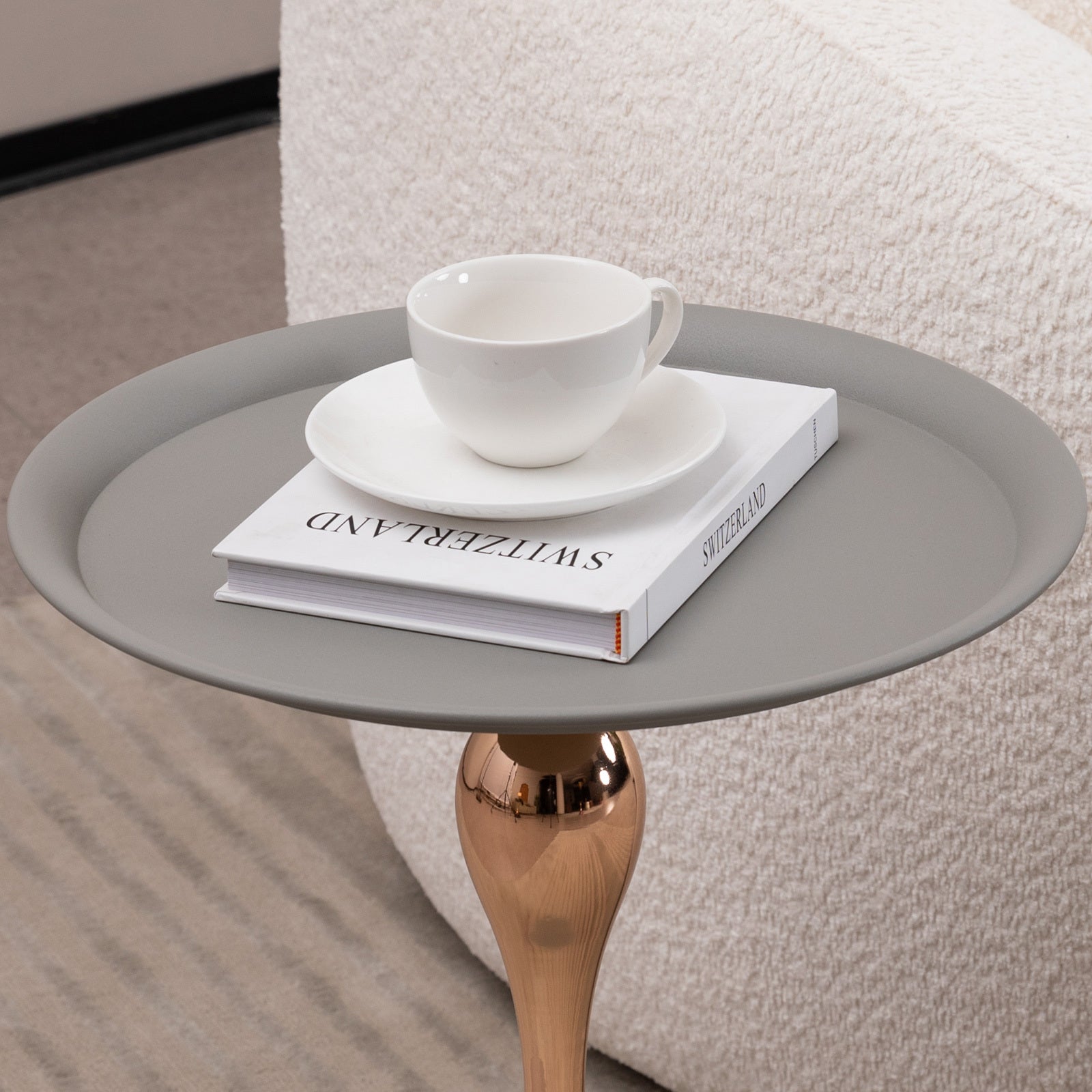 Close-up of Mermaid Tail End Coffee Table with a cup and book on its round gray surface, highlighting its modern accent table design.