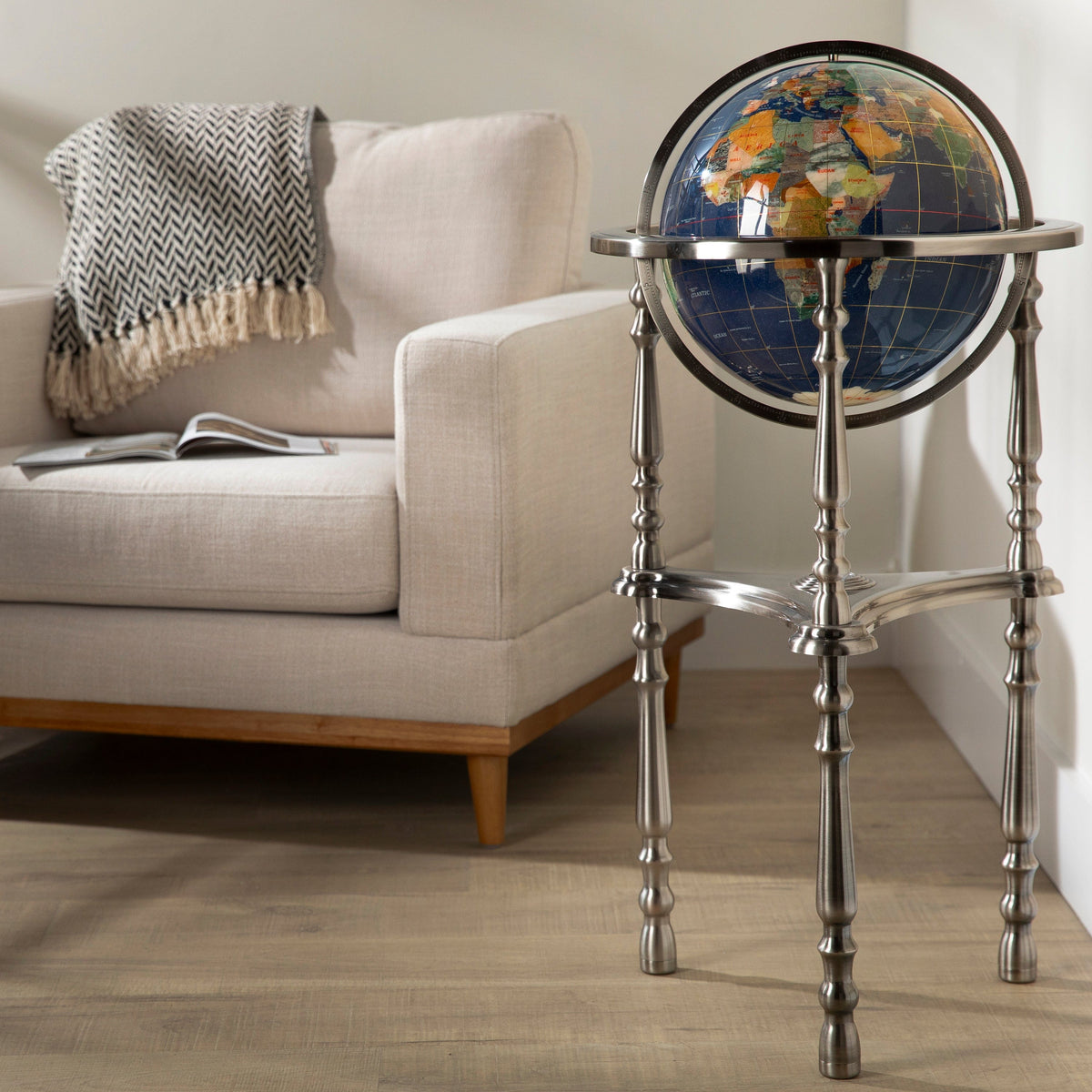 Globular world map on a stand in a living room setting with a couch and magazine.