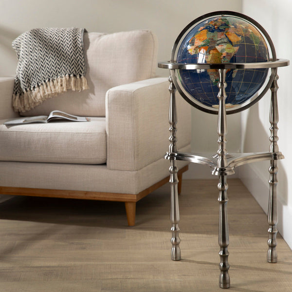 Globular world map on a stand in a living room setting with a couch and magazine.