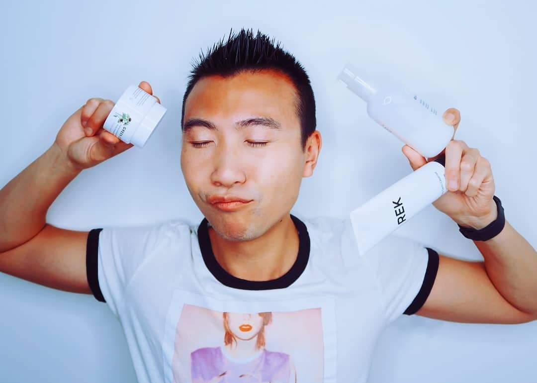 Person holding two bottles labeled 'REK' against a plain background