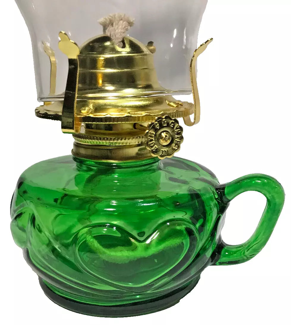 Green glass oil lamp with brass hardware on a white background