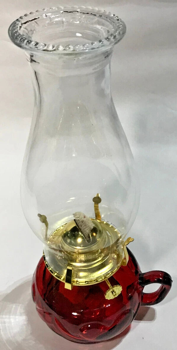 Clear glass oil lamp with red base on a white background