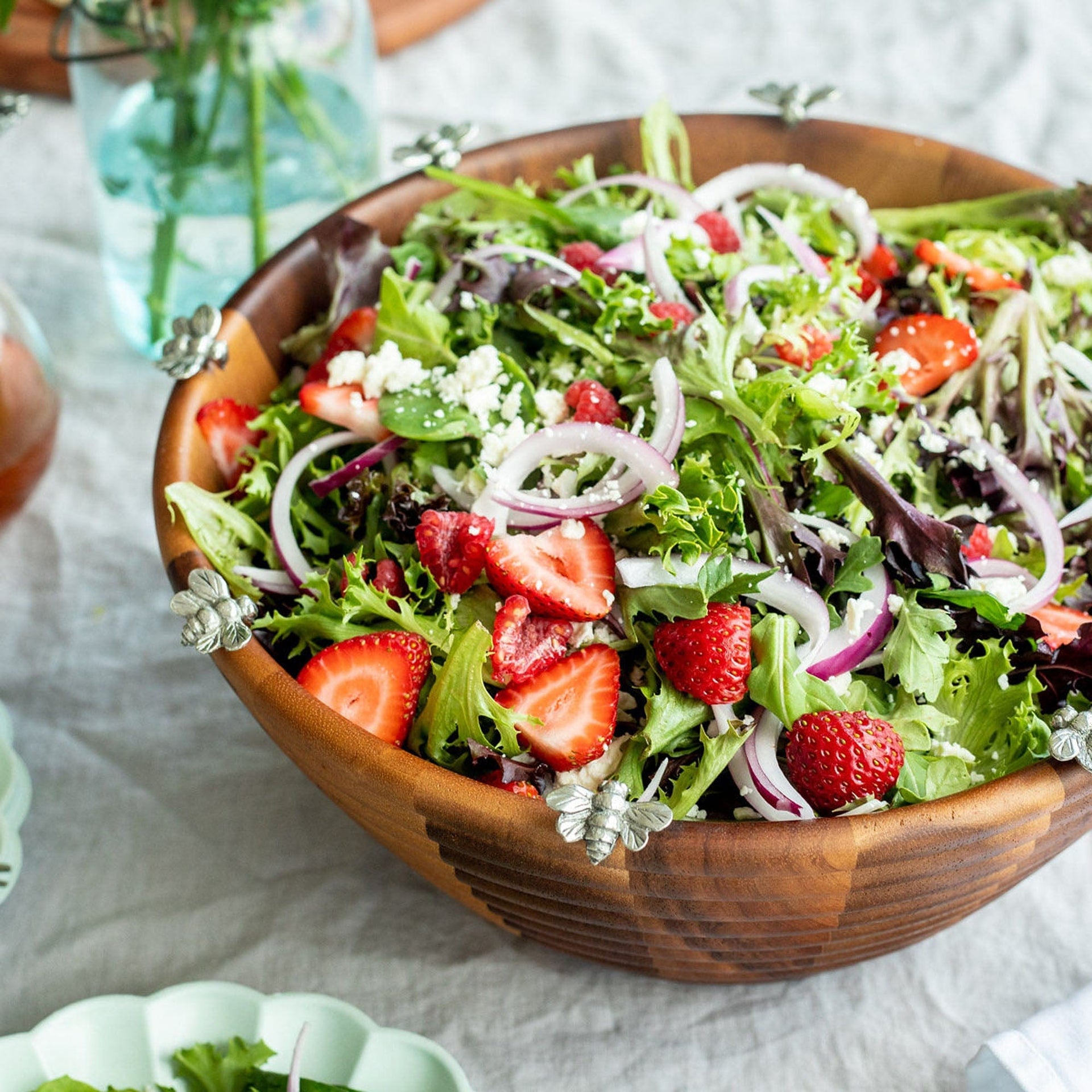 Wooden bowl of salad with strawberries on a white tablecloth