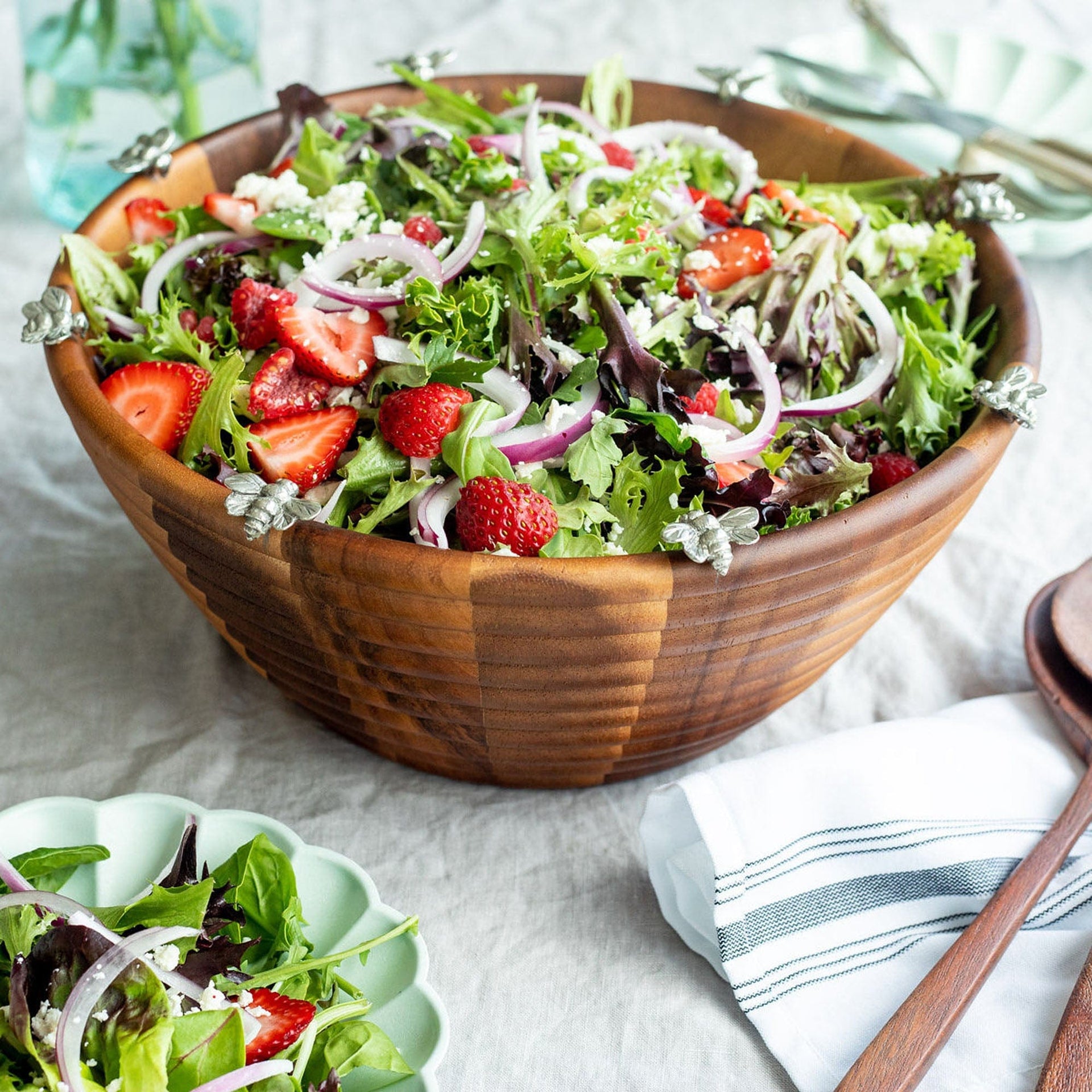 Wooden bowl filled with a fresh salad on a light surface.