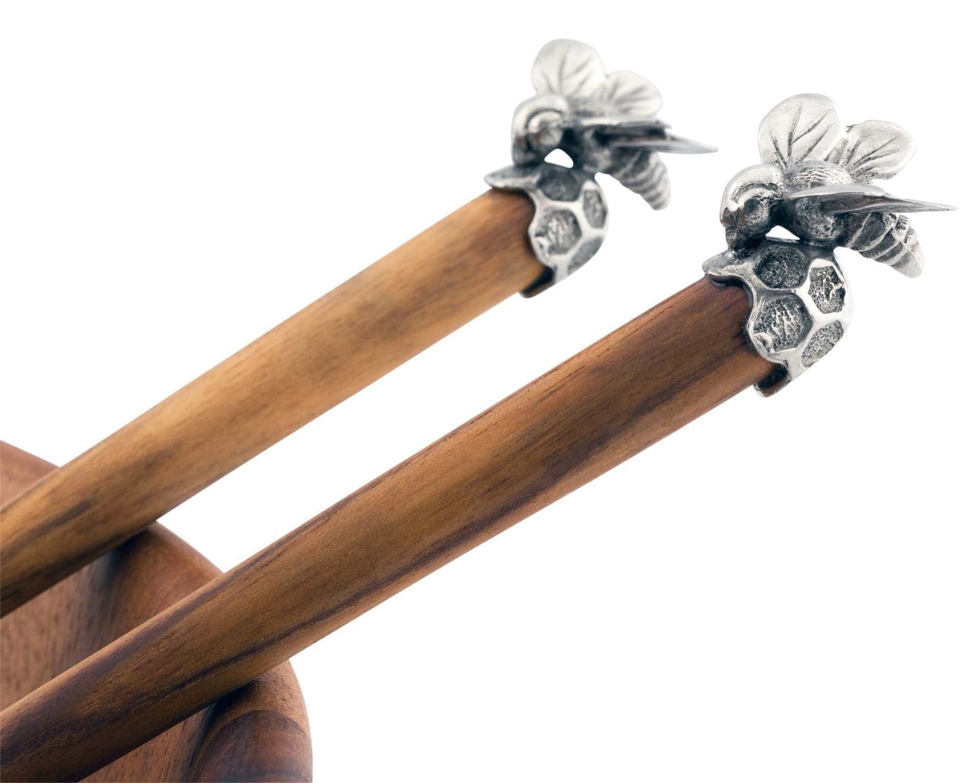 Wooden knitting needles with silver bee-shaped ends on a white background