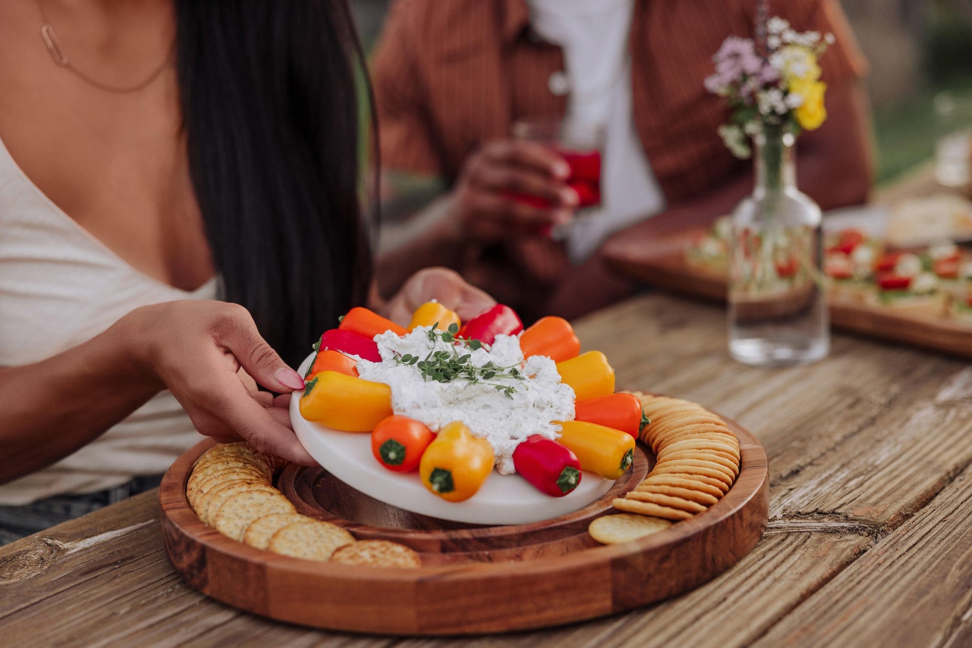 Dessert platter with fruit and cream on a wooden table with people in the background